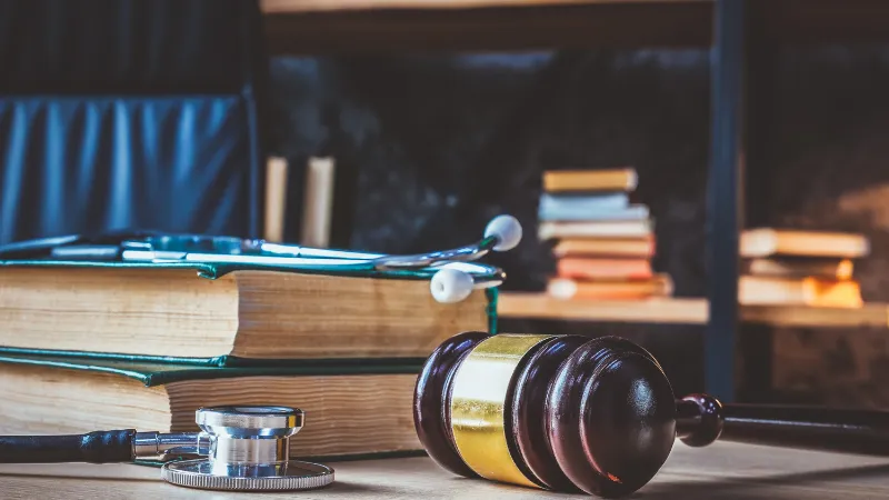 Medical negligence. Stethoscope on the book of laws and a gavel nearby.