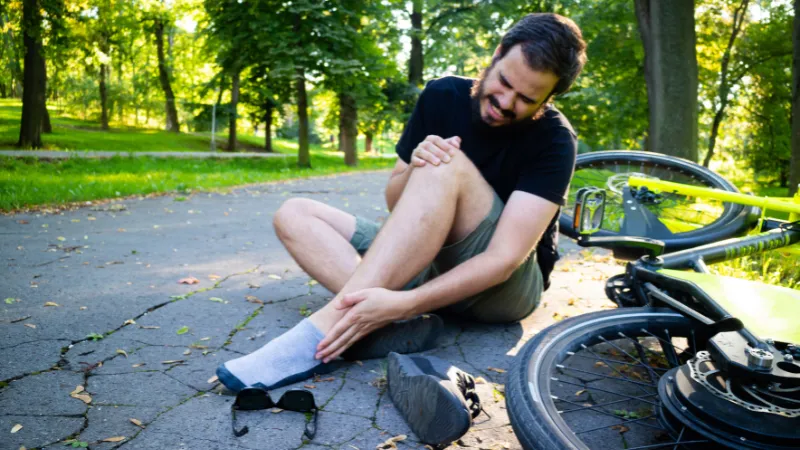 Man on the floor with injured ankle after an accident with electric bicycle