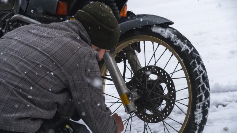 The man and his motorcycle. wheel. Rubber and tread are clogged with snow.